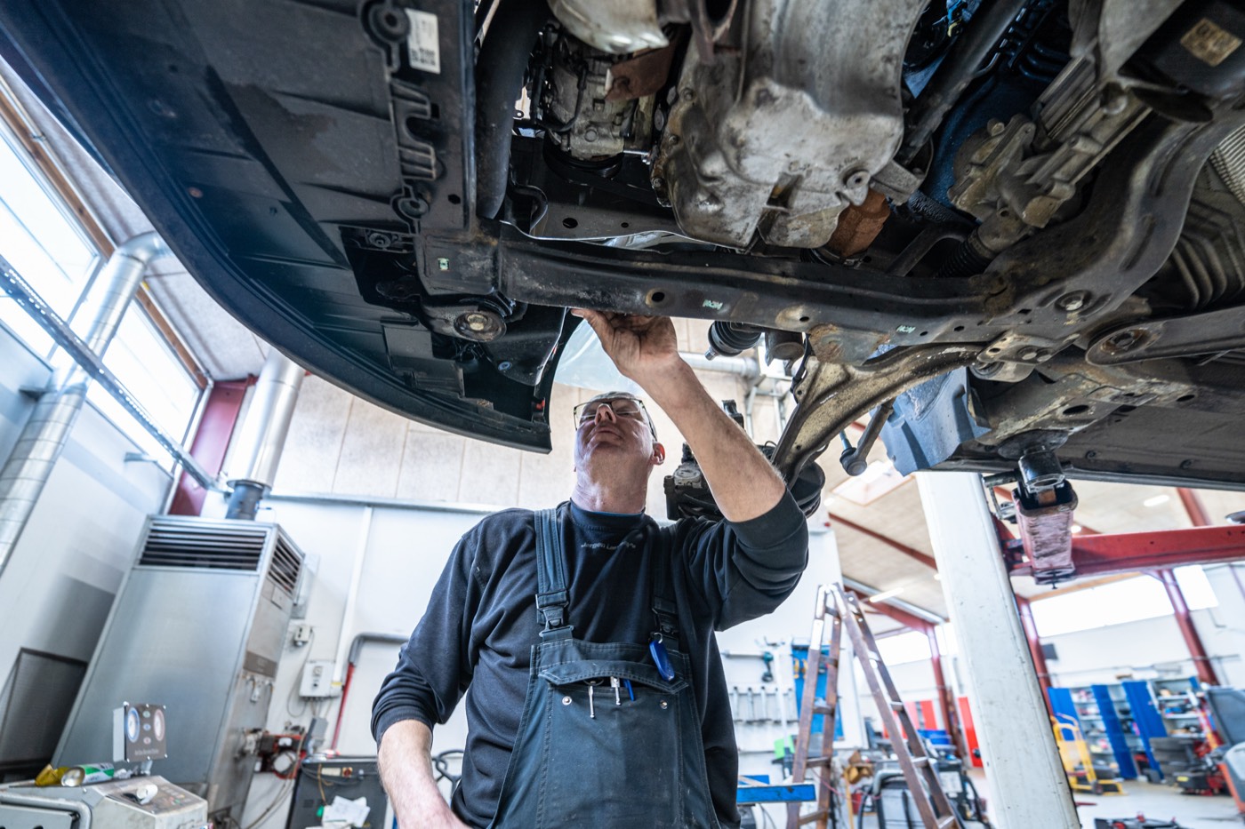 Mekaniker arbejder under en bil på liften